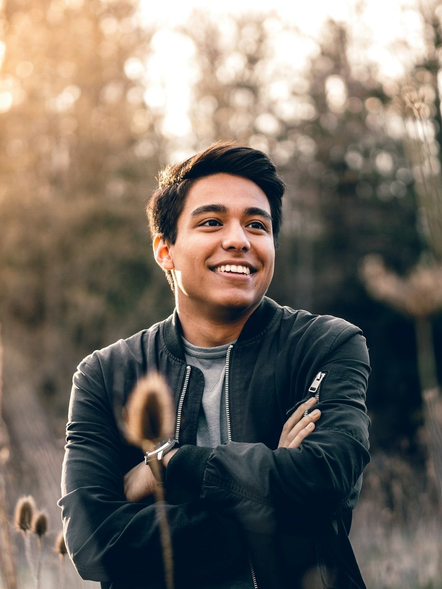 A young man smiling in warm outdoor light.
