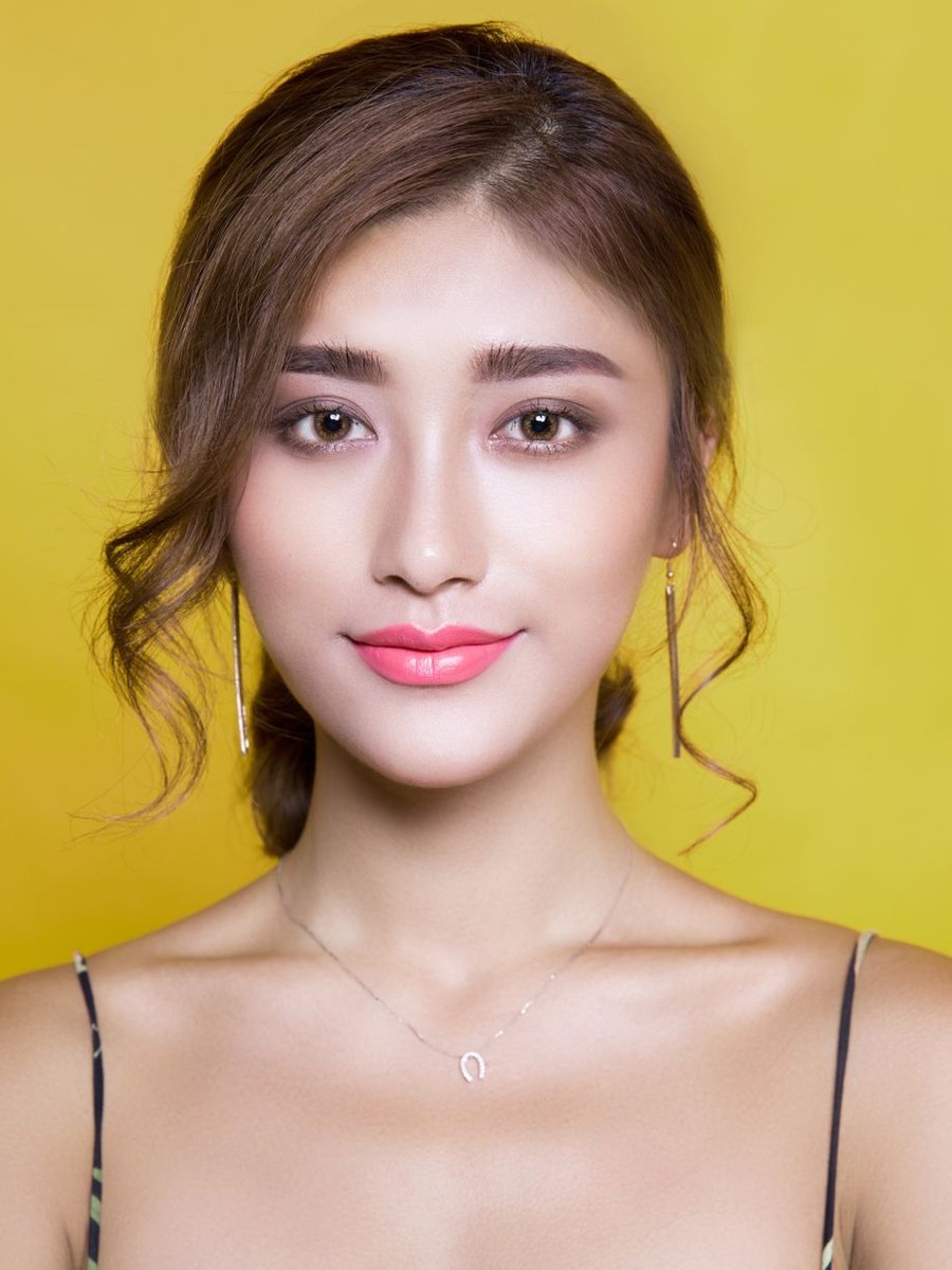 A woman smiling against a bright yellow background.