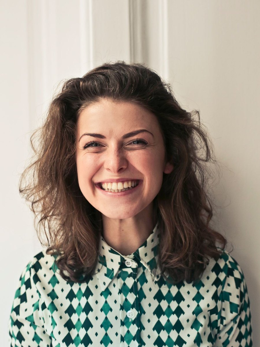 A woman in a patterned shirt smiling.