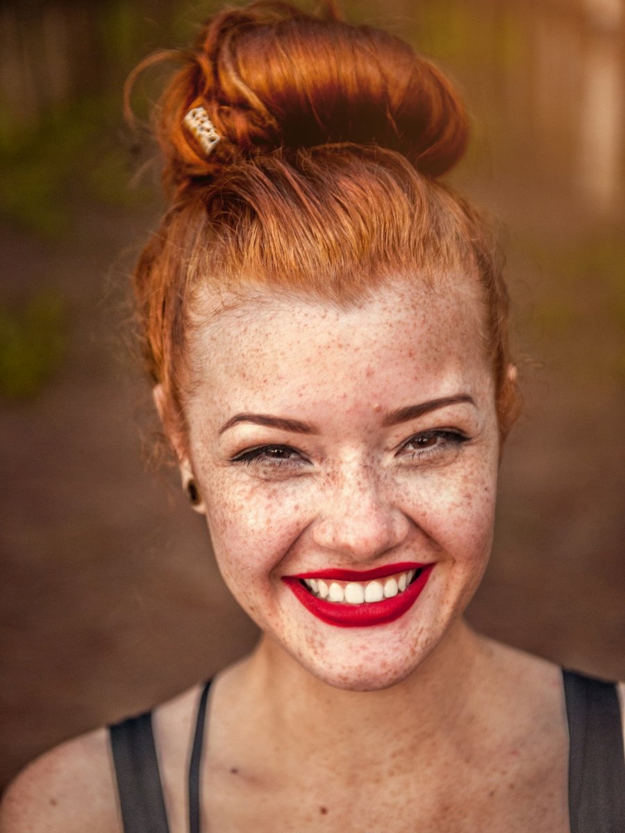 A woman with freckles smiling outdoors.