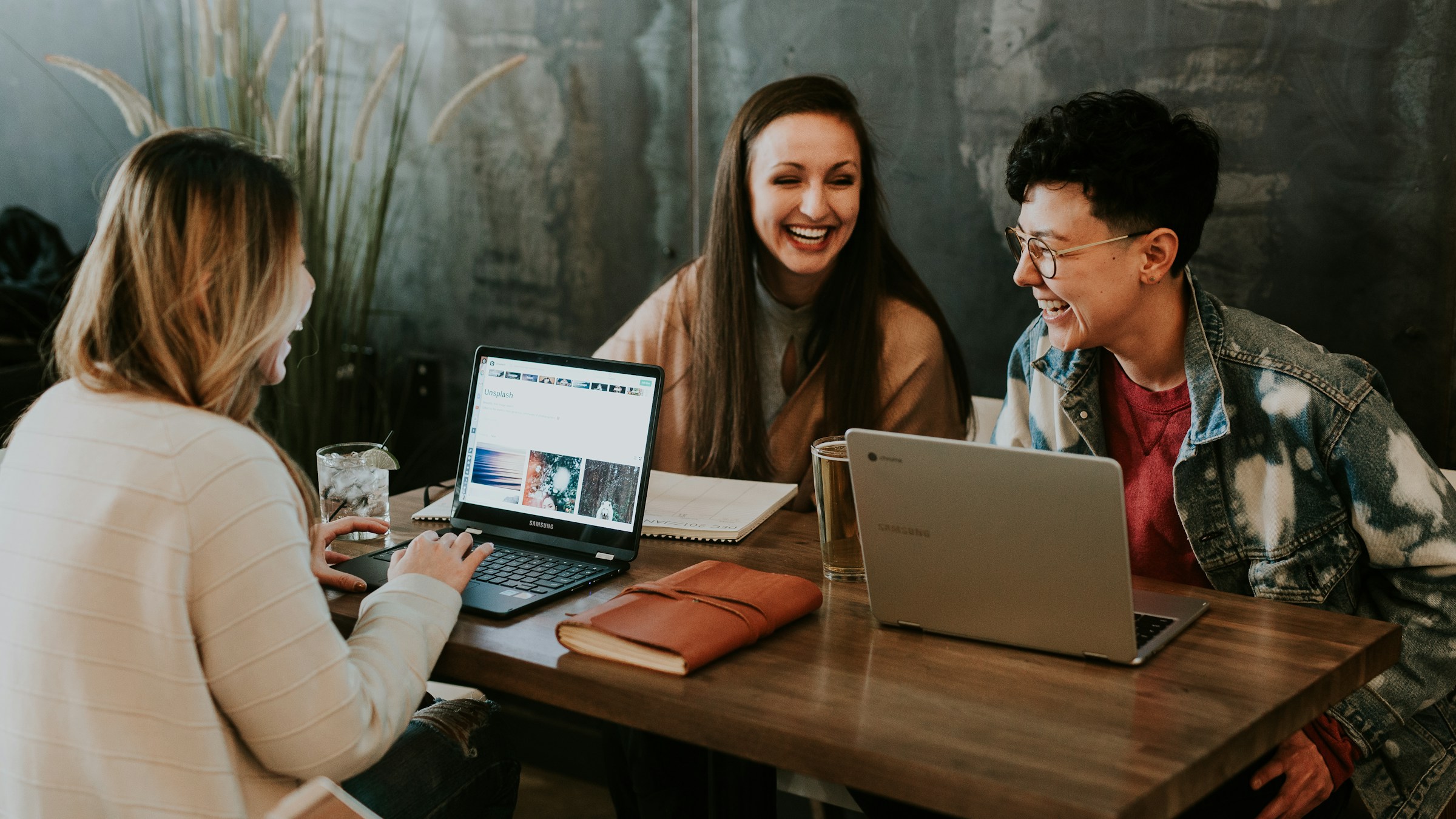 Three people laughing together while working side by side.