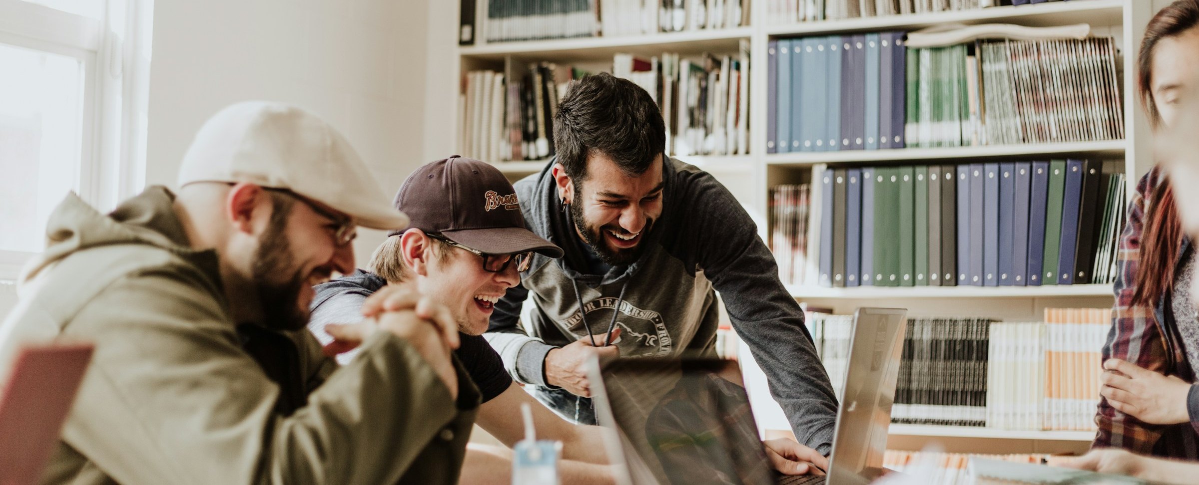 People collaborating and laughing together around a laptop.